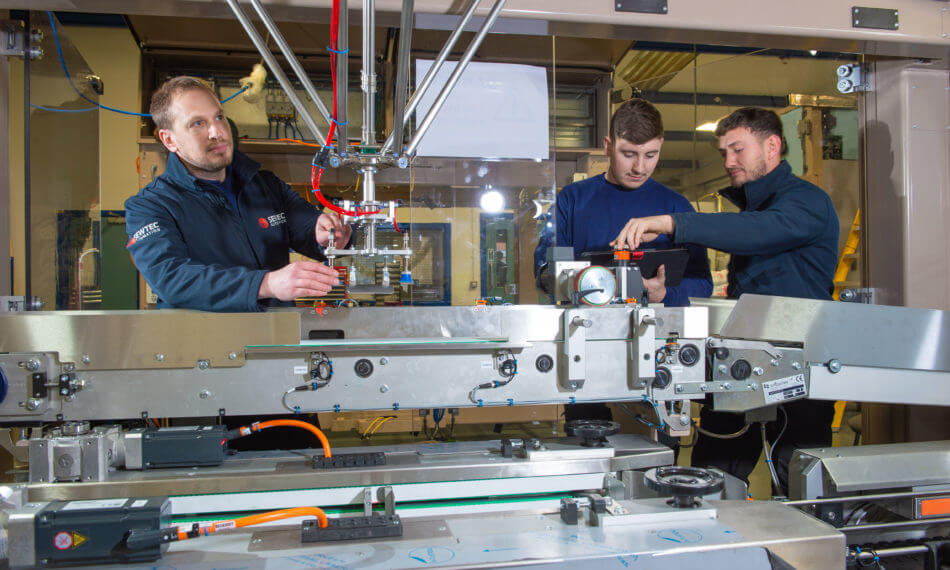 Three male employees adjusting machinery