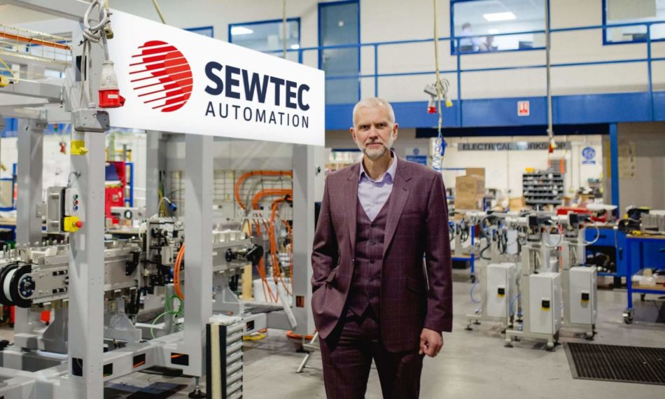 Managing director stood in front of company logo and machinery
