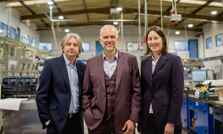 Two males and females smiling at camera in warehouse