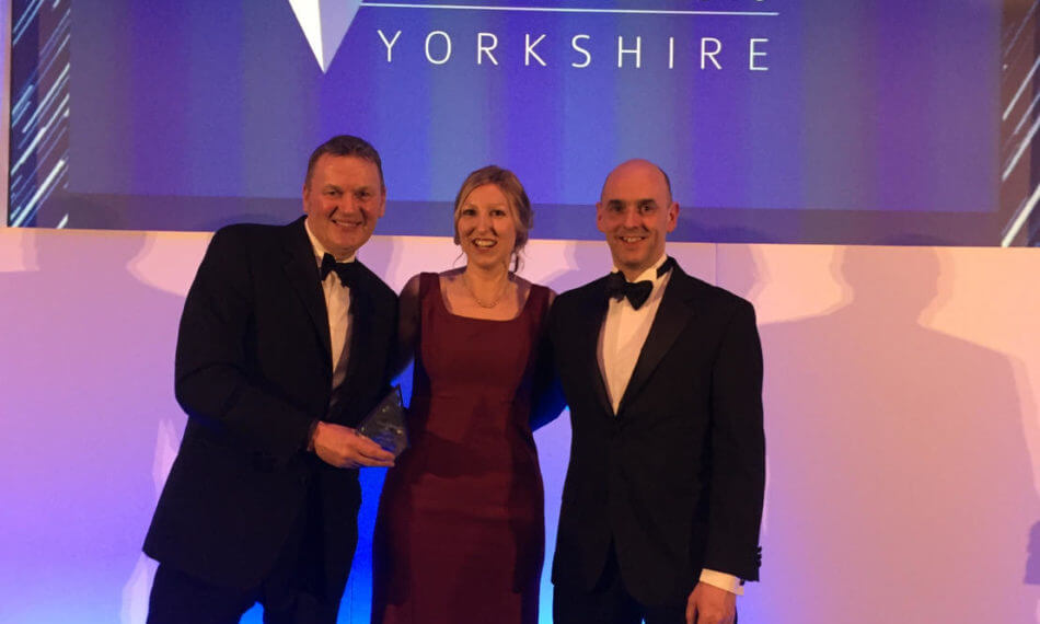 Two males and a female smiling on stage at the Business Masters 2019 Yorkshire awards