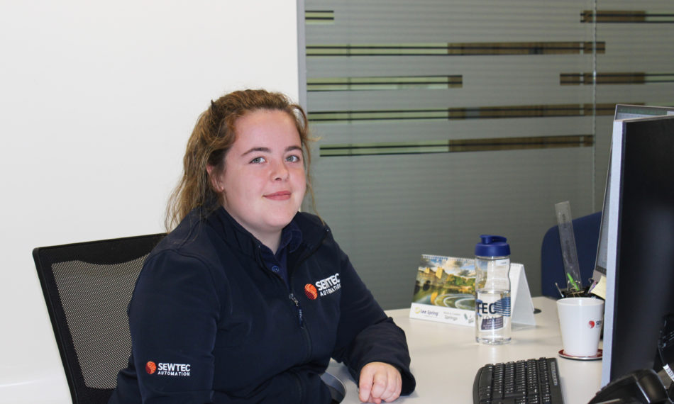 Female employee sat at desk smiling at camera