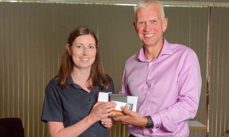 A man and woman both holding an award whilst smiling at the camera