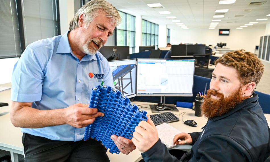 Two male employees discussing material for machinery