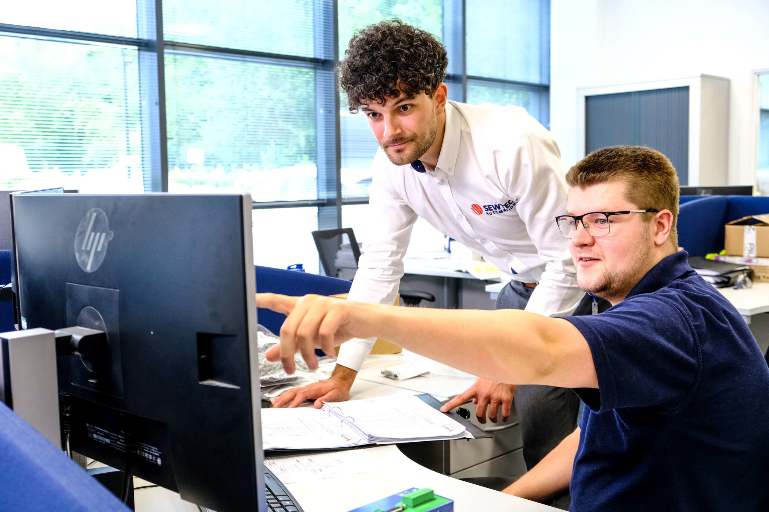 One employee pointing out something on a PC screen to another employee